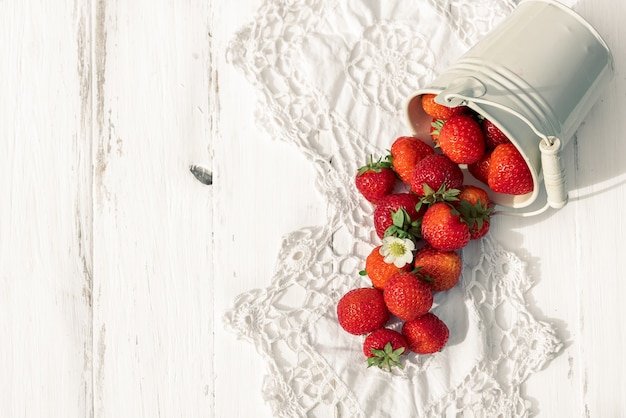 Strawberries on a white wooden old background, knitted napkin