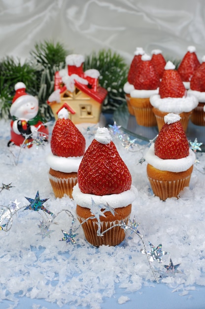 Foto fragole con panna montata a forma di cappello di natale su muffin