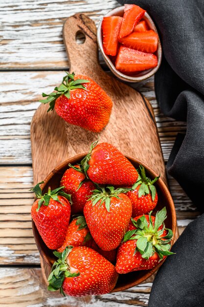 Strawberries in a wooden bowl on a chopping Board on white. Top view