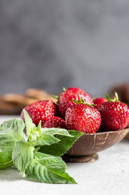 Fragole in una ciotola di legno con la menta.