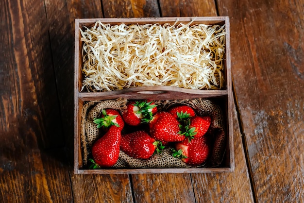 Strawberries in a wooden box on a wooden background