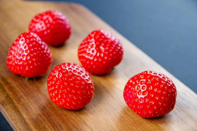 Strawberries on a wooden cutting board. black background