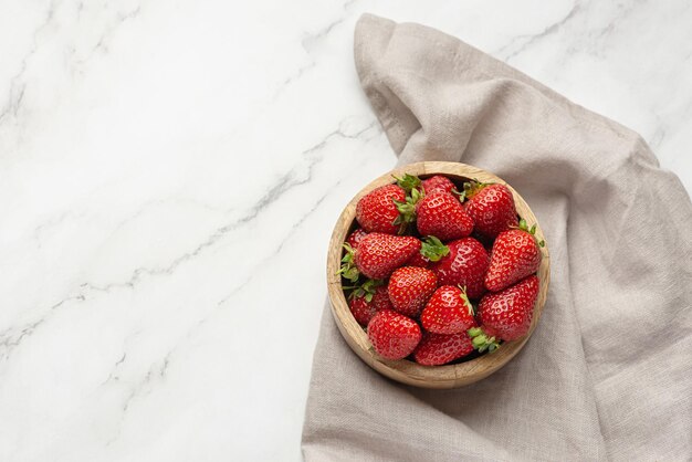 Strawberries in a wooden plate on a gray background