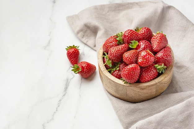 Strawberries in a wooden plate on a gray background