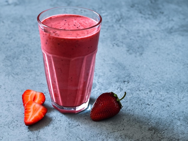 Strawberry banana non dairy smoothie in a tall glass on a light blue slate stone or concrete backgr