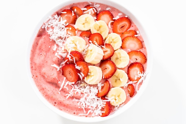 Strawberry and banana smoothie bowl garnished with coconut flakes and fresh fruits