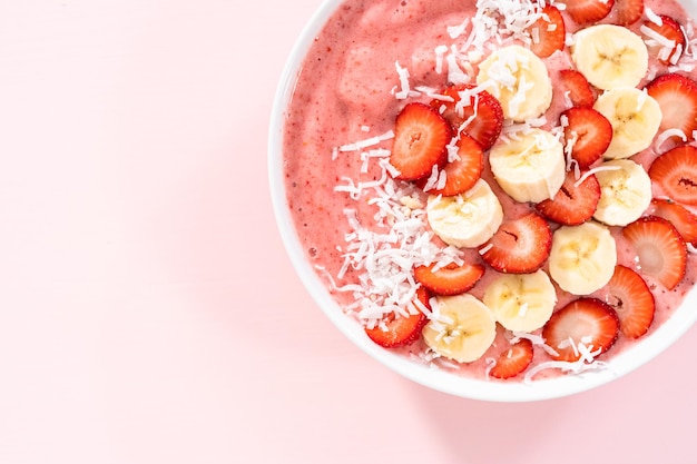 Strawberry and banana smoothie bowl garnished with coconut flakes and fresh fruits