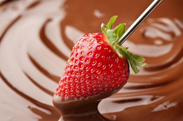 Strawberry being dipped into chocolate fondue