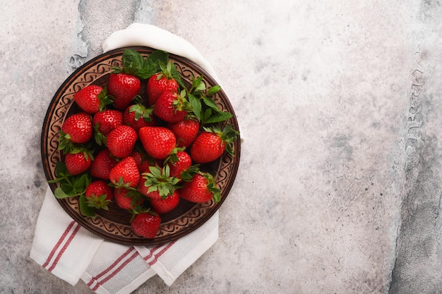 Strawberry berry Fresh red strawberry in ceramic rustic plate in basket on light gray concrete rustic table closeup Delicious juicy red berries Top view with copy space