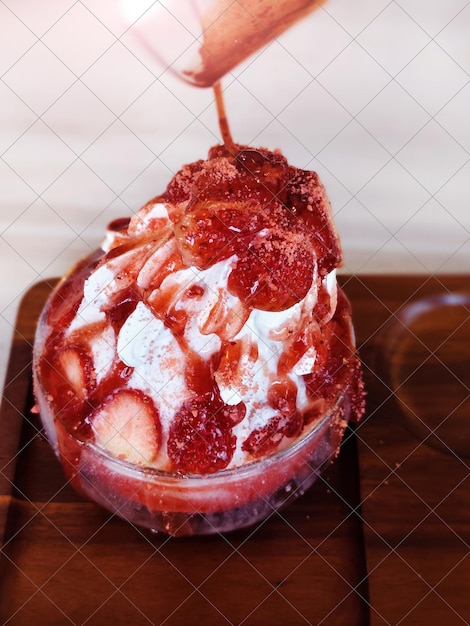 나무 트레이에 있는 유리 컵에 있는 딸기 빙수.