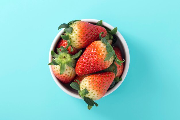 Foto fragola in ciotola su fondo blu