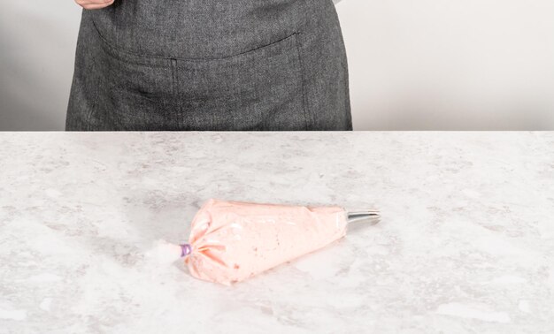 Strawberry buttercream frosting in a piping bag with a large metal piping tip.