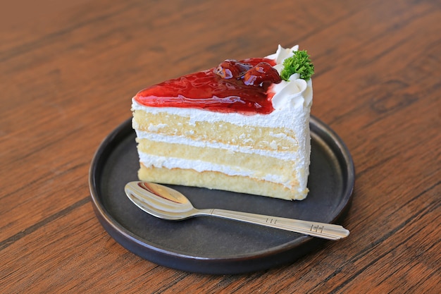 Strawberry cake in metal tray with spoon on wood table