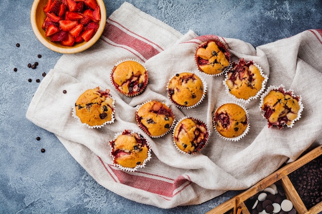 Strawberry chocolate cupcakes muffins on old wooden stand on concrete gray surface