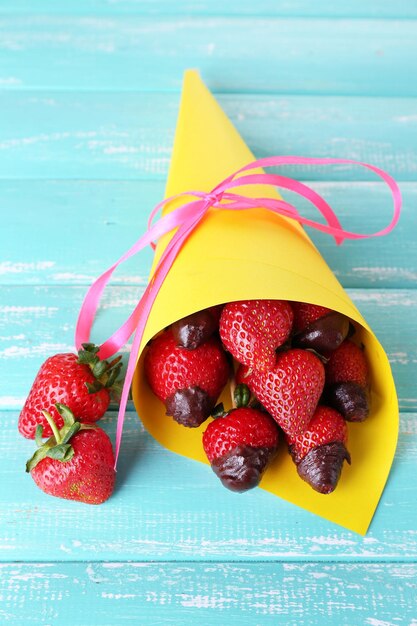 Strawberry in chocolate on skewers in paper bag on table close-up