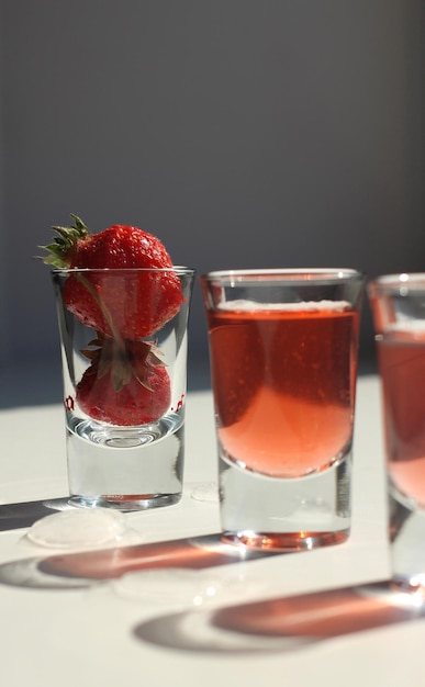 Strawberry compote tincture with ice in glass glasses with strawberries and ice cubes