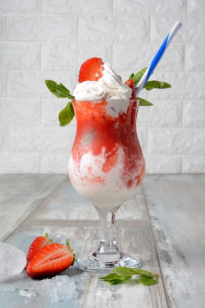 Strawberry dessert with whipped cream and mint served in a glass cup