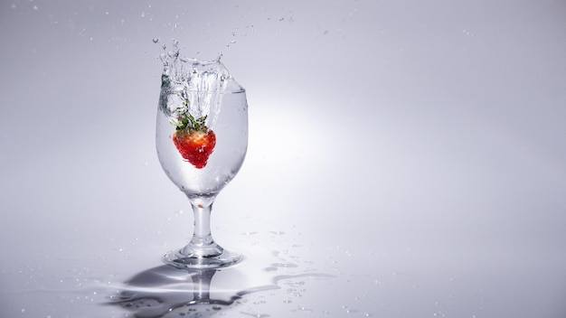 The strawberry drops in to a glass of water