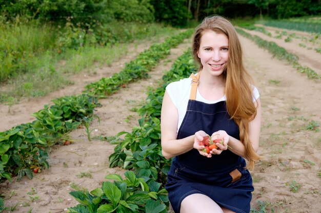 Strawberry farm farmer holding a heap of strawberries and smiling