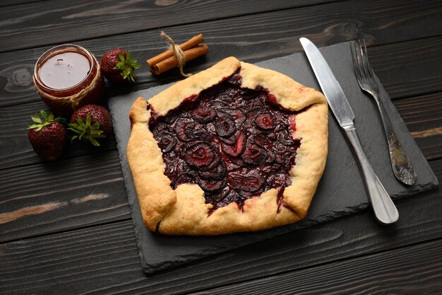 Strawberry galette on dark wooden background Homemade