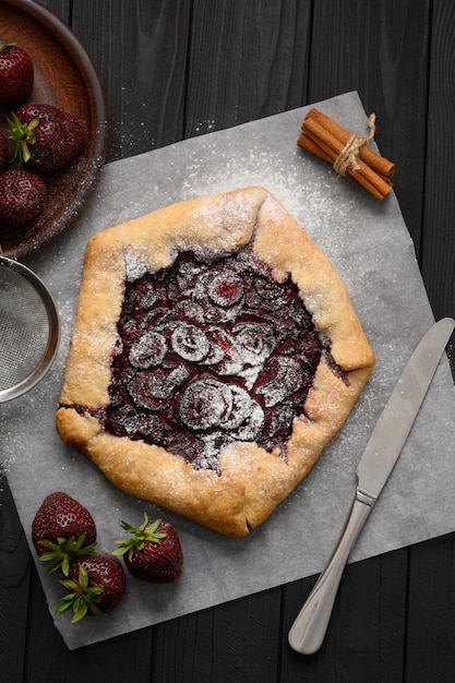 Strawberry galette on dark wooden background Homemade