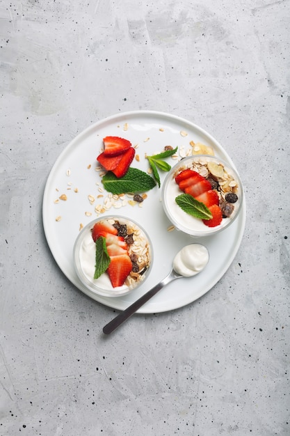 The strawberry and granola in the yogurt. glass bowls with cream and strawberries. top view