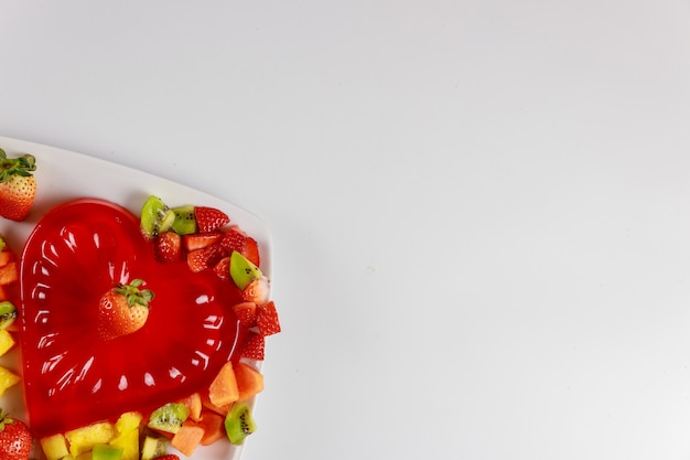 Strawberry heart shape gelatin with fruits on white plate