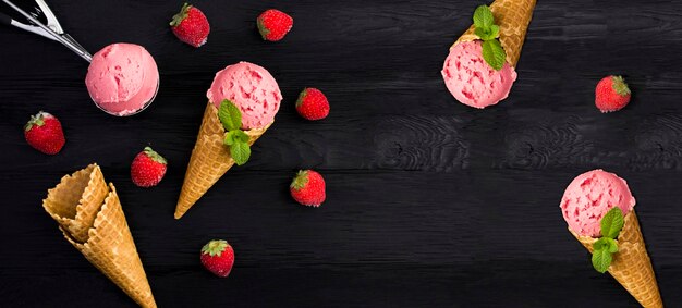 Foto gelato alla fragola in un cono di waffle sullo sfondo nero copia spazio vista dall'alto