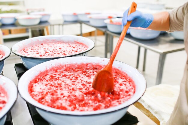 Strawberry jam cooking process. Wooden spoonmixing jam. Organic traditional jam manufacturing.