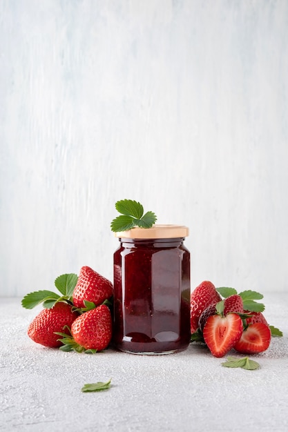 Photo strawberry jam in glass jar and  pieces of strawberry. preserving. home preservation, food preparation.