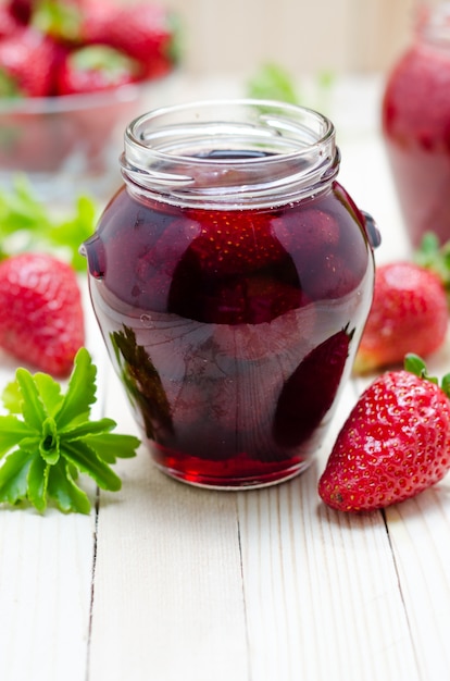 Strawberry jam in a jar and fresh strawberries on the light wooden table