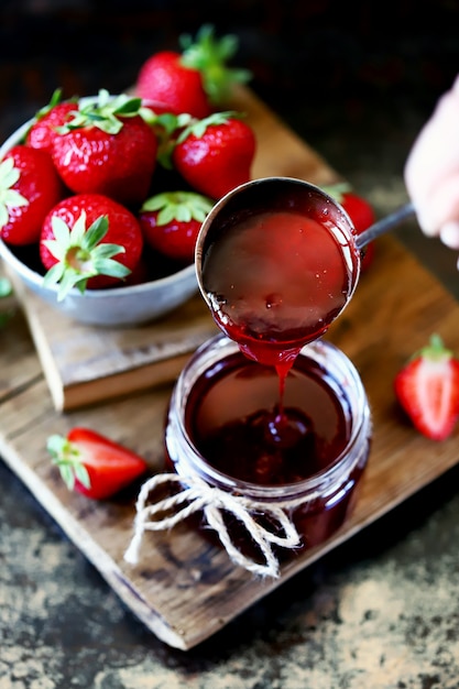 Strawberry jam pours into a jar.