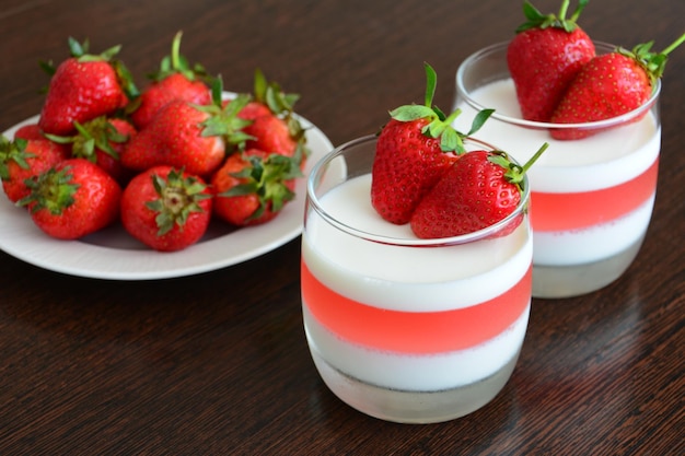 strawberry jelly dessert in the glasses decorated with strawberry on the wooden kitchen table