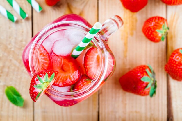 Strawberry lemonade with ice in mason jar on a wooden table