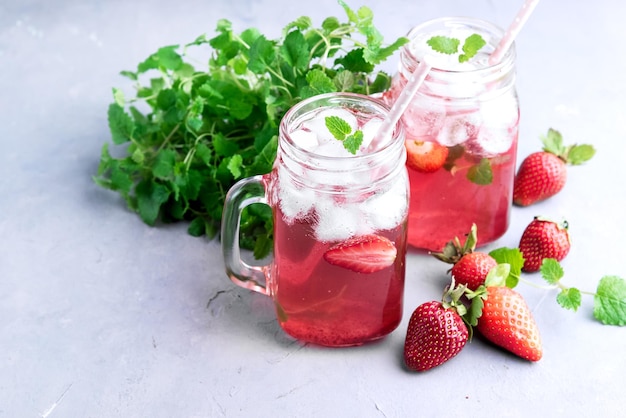 Strawberry lemonade with ice and mint in glass mug jars