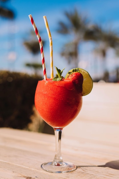 A strawberry margarita with straws and a straw