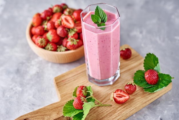 Strawberry milk shake in a glass jar and fresh strawberries with leaves