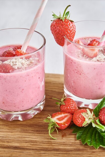 Milk shake alla fragola in vetro con paglia e frutti di bosco freschi