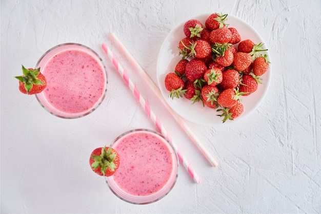 Milk shake alla fragola in vetro con paglia e frutti di bosco freschi