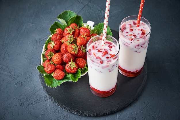 Strawberry milk smoothie in glass with straw and fresh berries