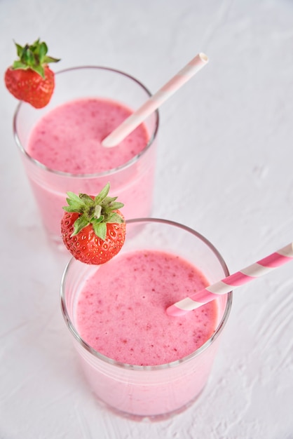 Strawberry milk smoothie in glasses with straws