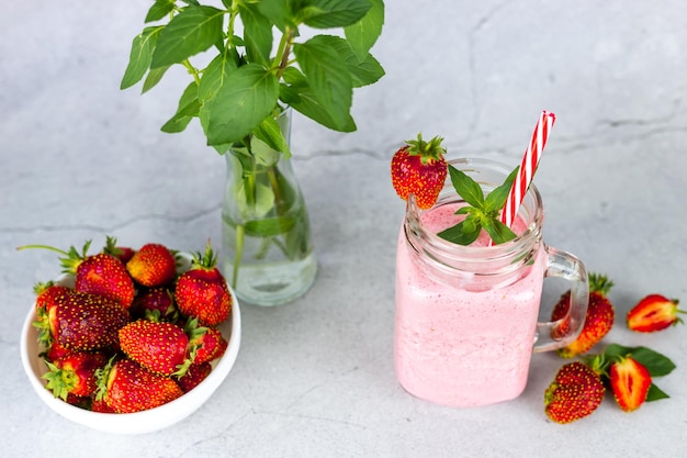 Strawberry milkshake in glass jars with fresh strawberries and mint Healthy summer drink for a vegan diet