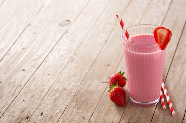 Strawberry milkshake in glass on wooden table