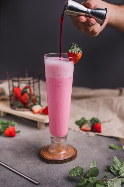 Photo a strawberry milkshake is being poured into a glass.