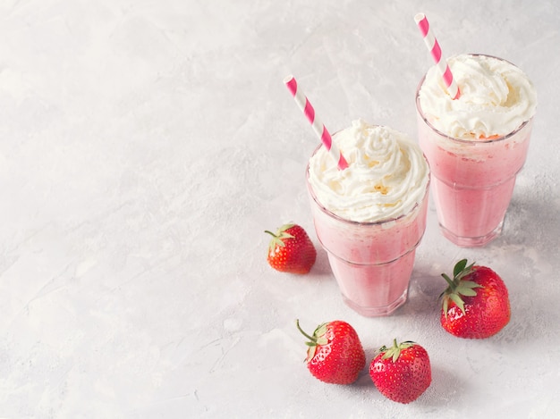 Strawberry milkshake or smoothie and fresh raw berries on white