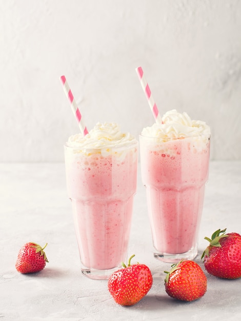 Strawberry milkshake or smoothie and fresh raw berries on white