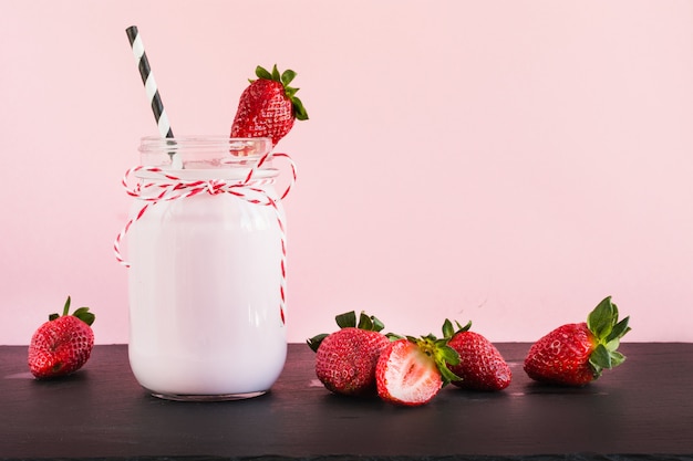 Strawberry milkshake with berry in mason jar on pink. Close up. Summer drink.