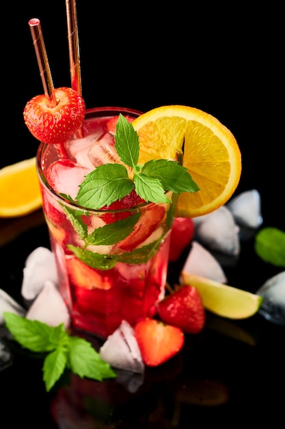 Strawberry mojito with lemon and mint isolated on black background with reflection