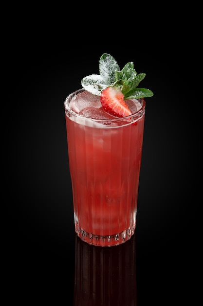 Foto mojito alla fragola con rum alla menta e ghiaccio in un bicchiere su uno sfondo scuro con riflesso