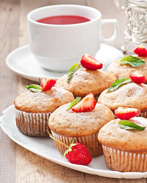 Strawberry muffin on a white plate with a fresh strawberry